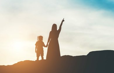 Silhouette of mother with her daughter standing and sunset